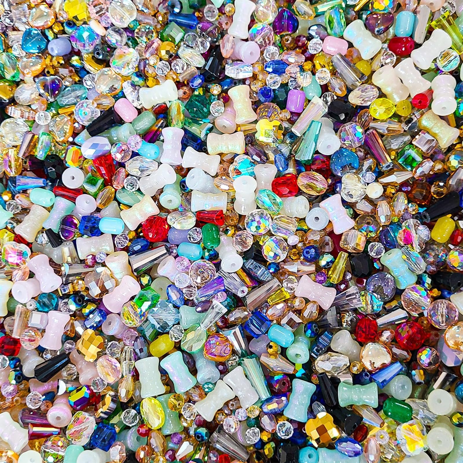 Assorted glass beads in various shapes, sizes, and colors, including faceted crystals and tube beads, filling the frame.