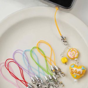 Assorted colorful nylon cords with lobster clasps and decorative charms attached to a phone case