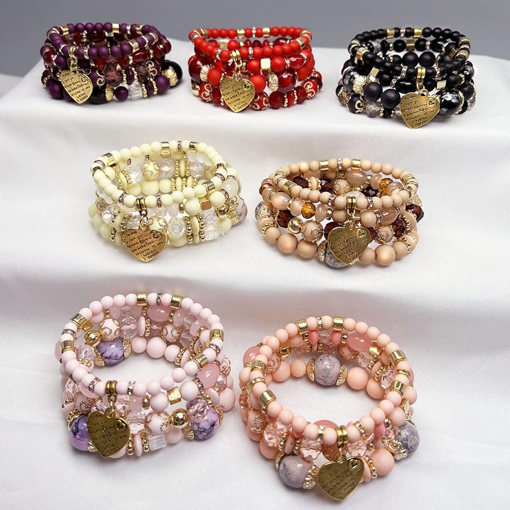 Six stacks of colorful beaded bracelets with gold heart charms, displayed on a white surface.