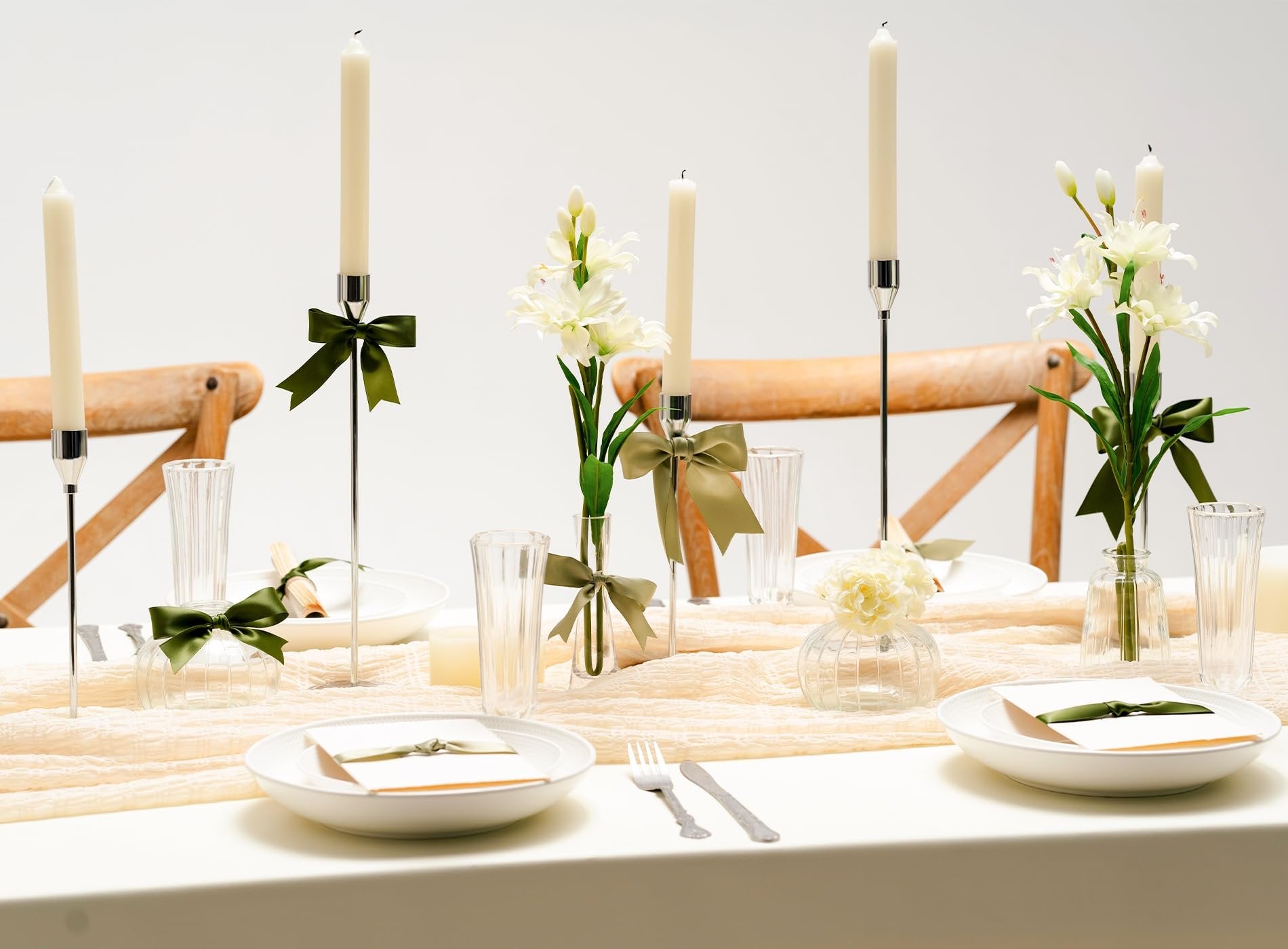 Table setting with candles, flowers, and plates decorated with green ribbon for a formal event.