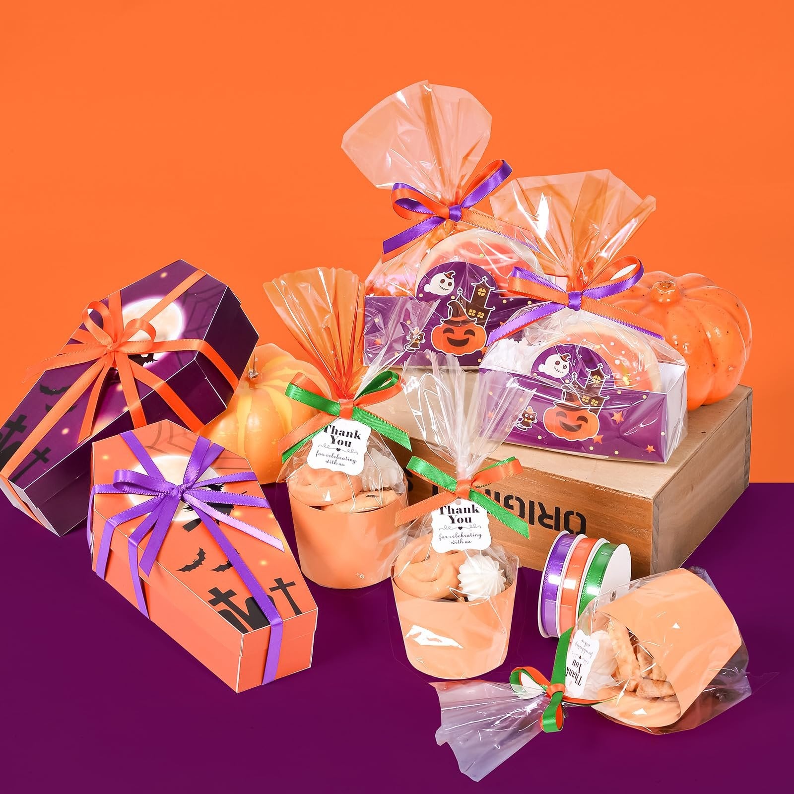 Halloween-themed gift boxes and treat bags filled with cookies and meringues, arranged with decorative pumpkins.
