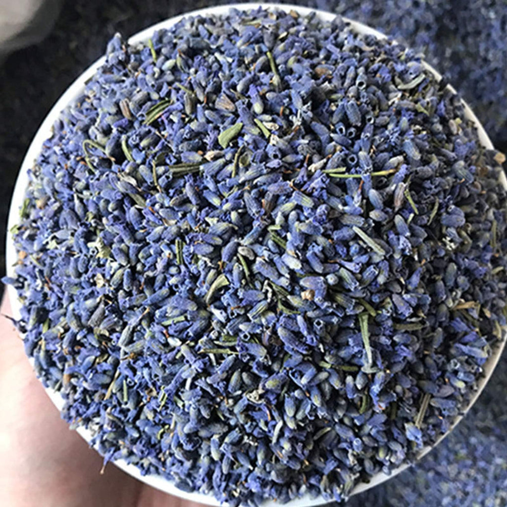 Close-up overhead view of dried lavender buds in a white bowl, showing their purple and green hues.