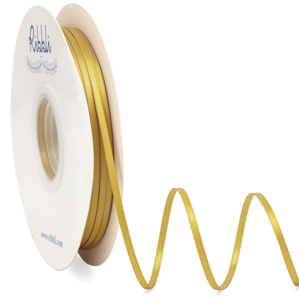 Gold satin ribbon on a spool, with the ribbon unspooling in a wave pattern against a white background.