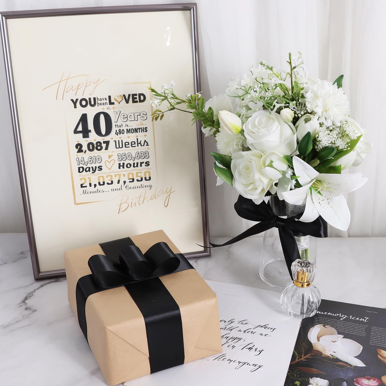 Framed 40th birthday milestone sign with gift and floral arrangement on a marble surface.