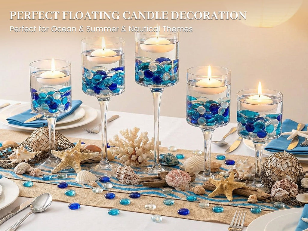 Floating candles in glass vases filled with blue and clear glass gems, arranged on a table with seashells and starfish.