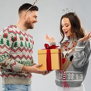 Man in ugly Christmas sweater giving a gift-wrapped box to a woman in a reindeer sweater