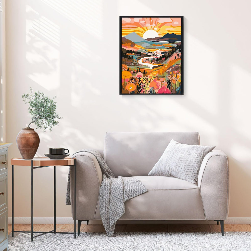 Framed landscape painting of a valley with a river and sunburst, displayed above a sofa.