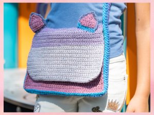 Crocheted multicolor yarn purse with cat ears worn by a child