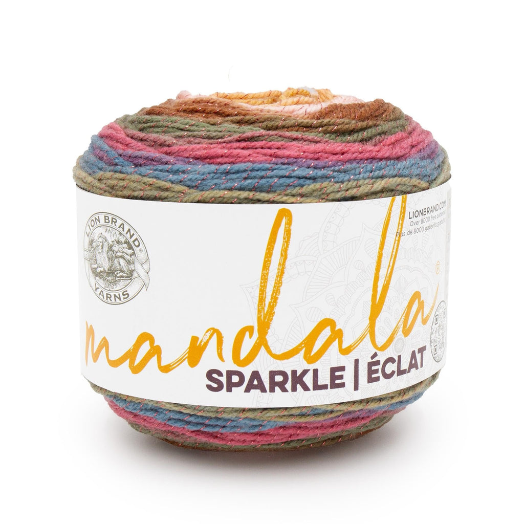 Cake of multicolor sparkle yarn with pink, blue, green, and brown stripes, featuring a white label with brand logo and product name.