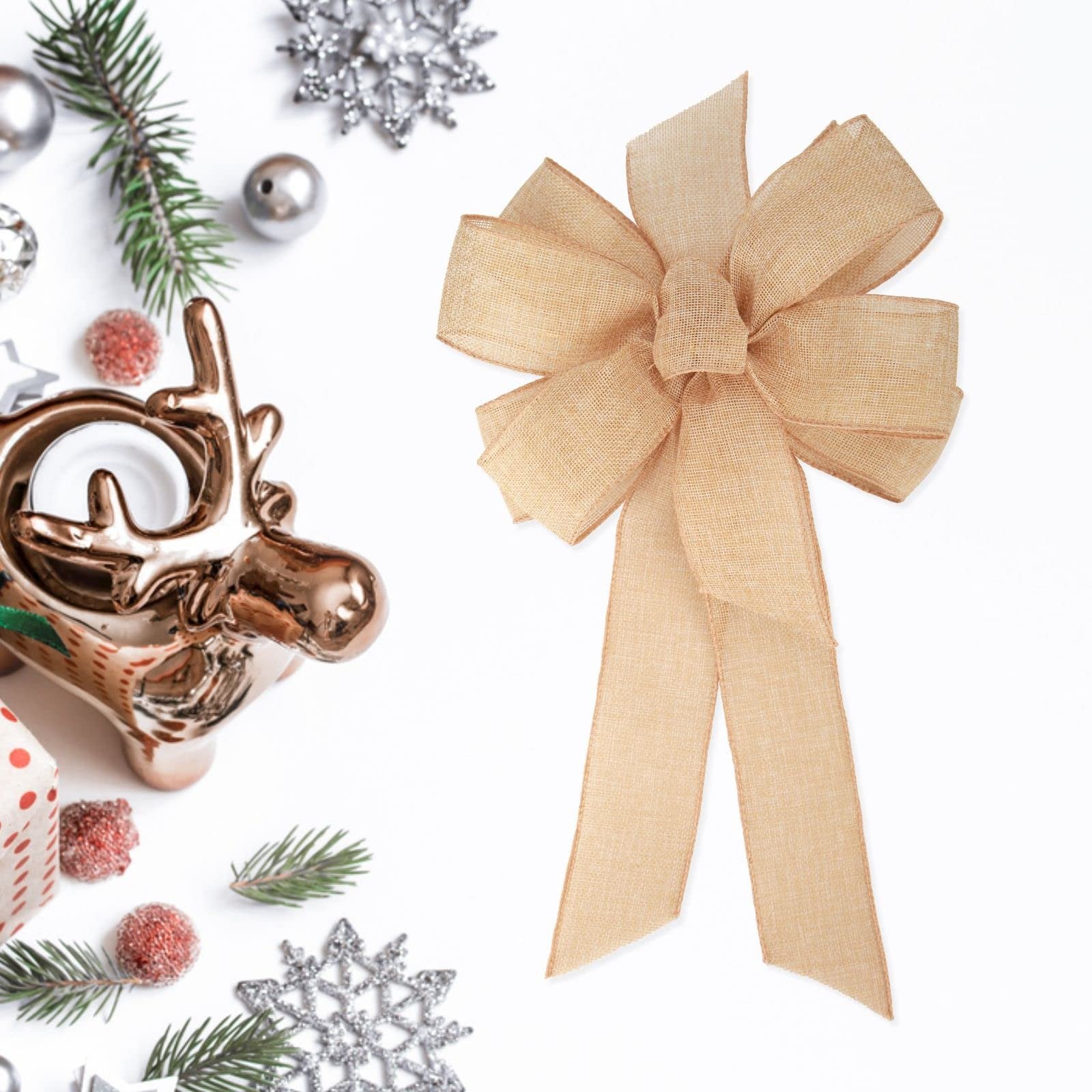 Burlap bow with streamers on a white background with Christmas decorations including a reindeer candle holder and pine sprigs