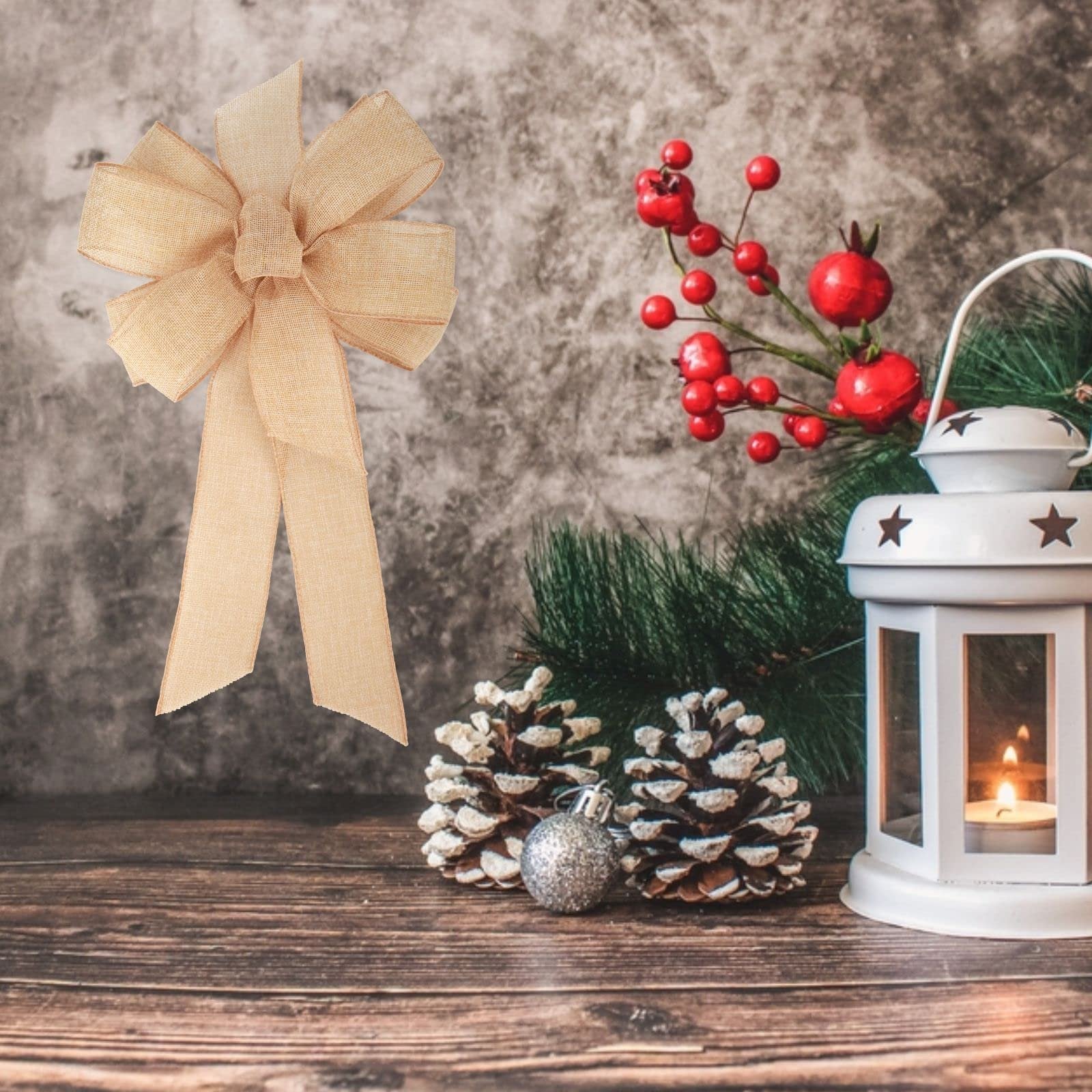 Burlap bow with pine cones, red berries, and a lantern on a wooden surface