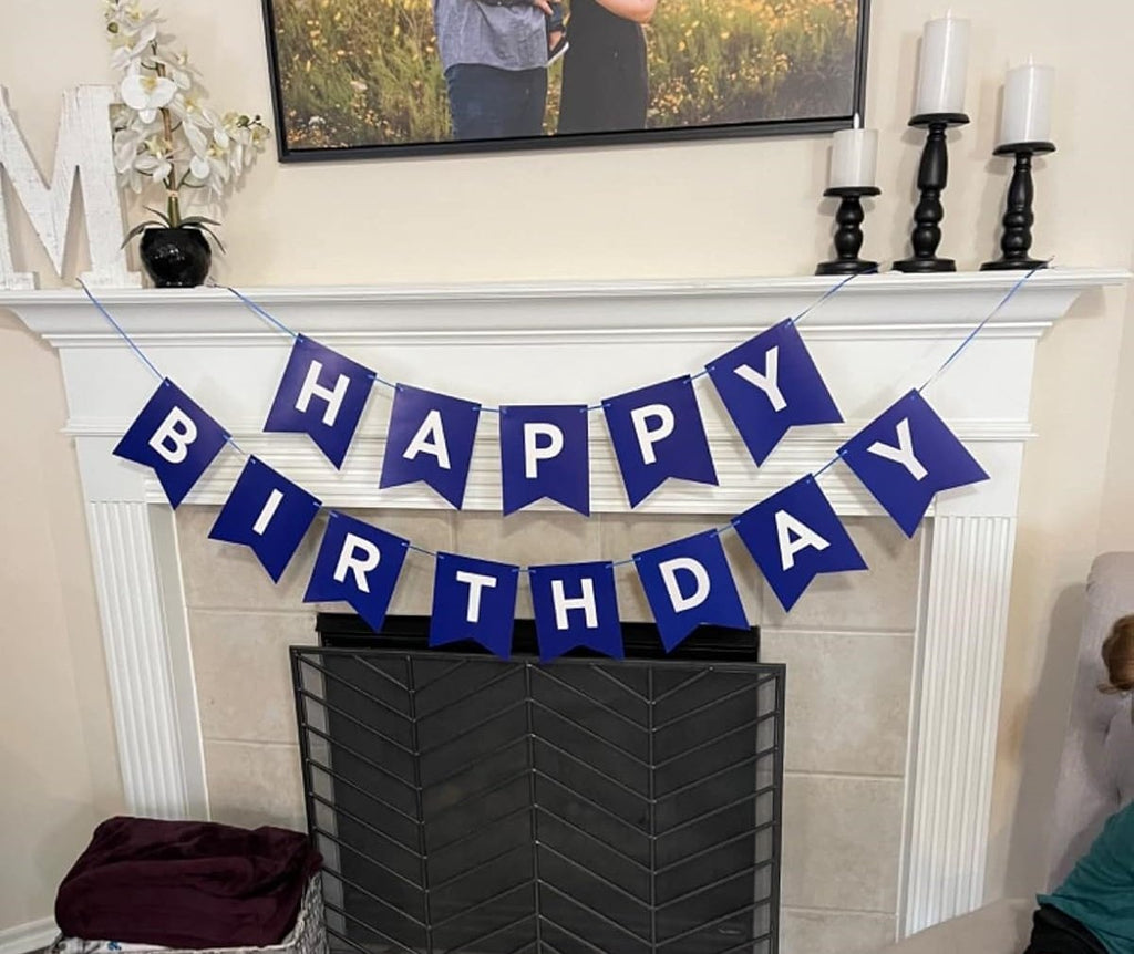 Blue and white 'Happy Birthday' banner strung across a fireplace mantel with decorative items.