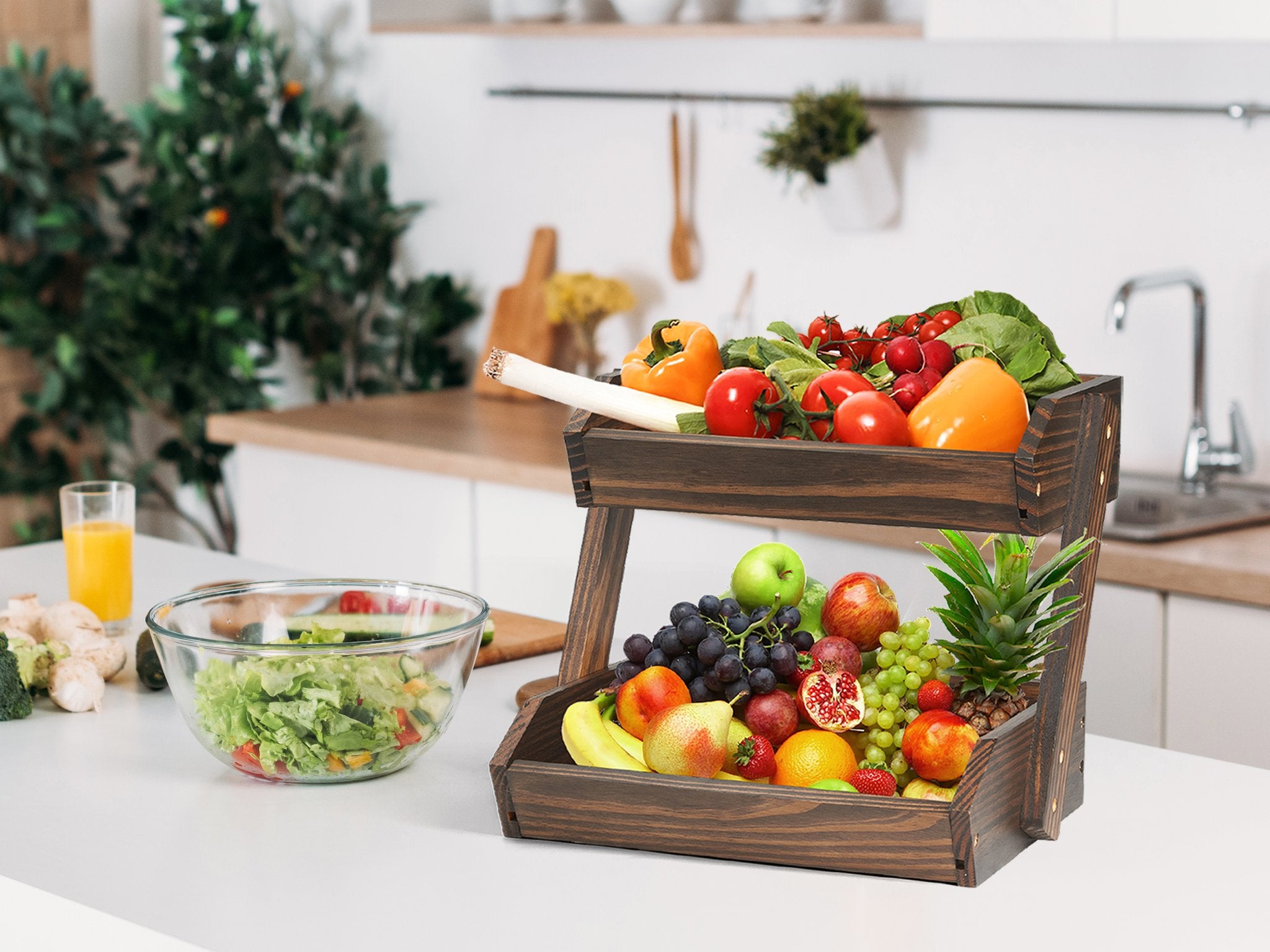 Two-tier wooden fruit basket filled with various fruits and vegetables on a kitchen counter.