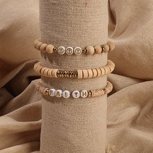 Three handmade bracelets with wooden beads and letter beads spelling 'FAITH' on one, displayed on a textured cylinder.