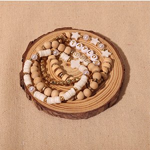 Clay bead bracelets with letter beads spelling 'TAYLOR' and star charms, arranged on a wooden slice.