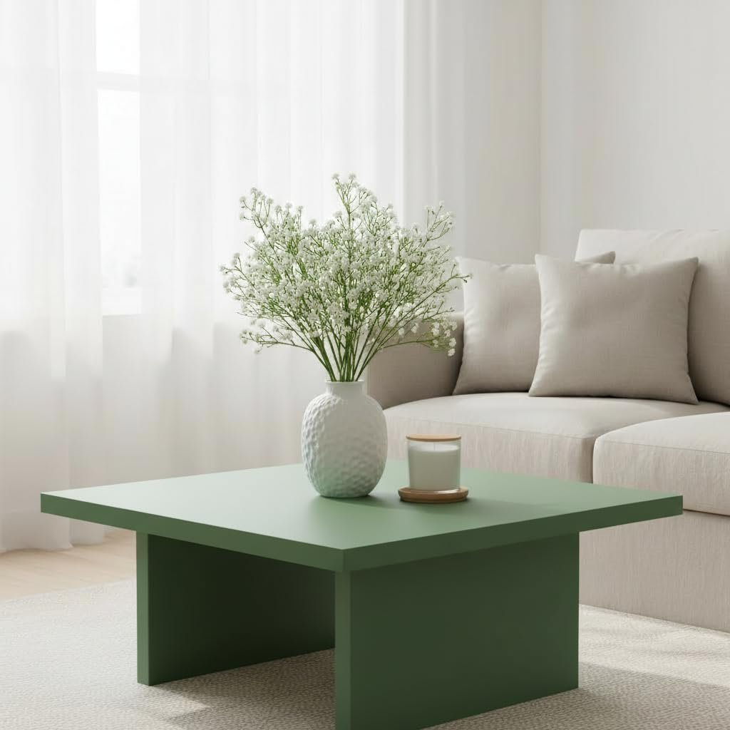 White baby's breath artificial flowers in a textured vase on a green coffee table with a candle.
