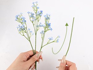 Hands holding a blue artificial baby's breath bouquet with flexible stems, showing stem bending.