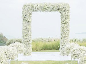 Wedding arch and aisle decor made of white artificial baby's breath flowers outdoors