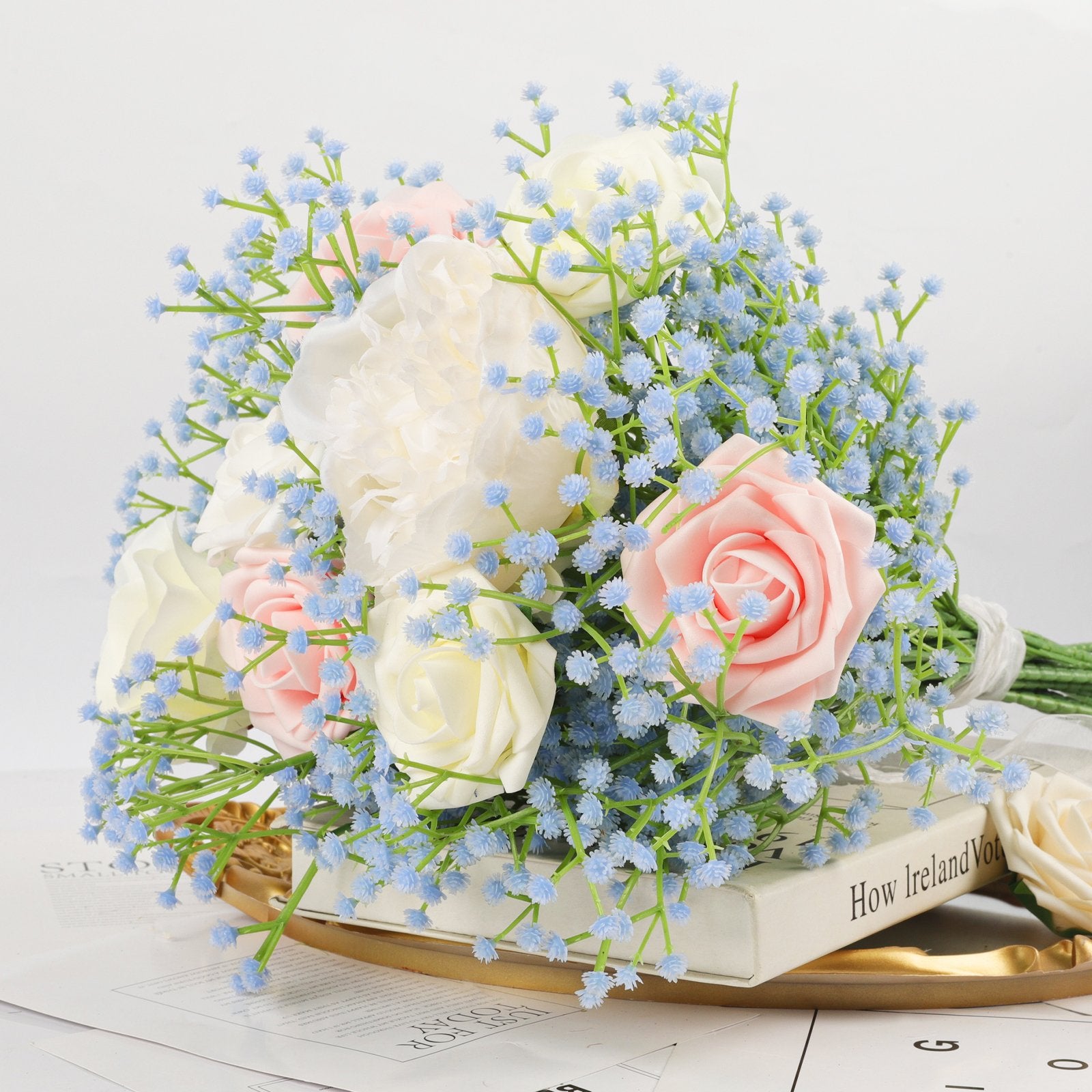 Bouquet of artificial baby's breath with pink and white roses, arranged on a decorative tray.