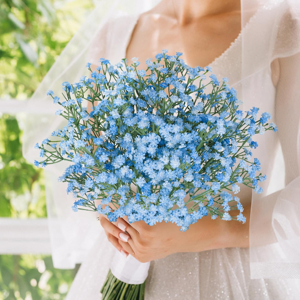 Bride holding a bouquet of blue artificial baby's breath flowers with a white ribbon on the stems.