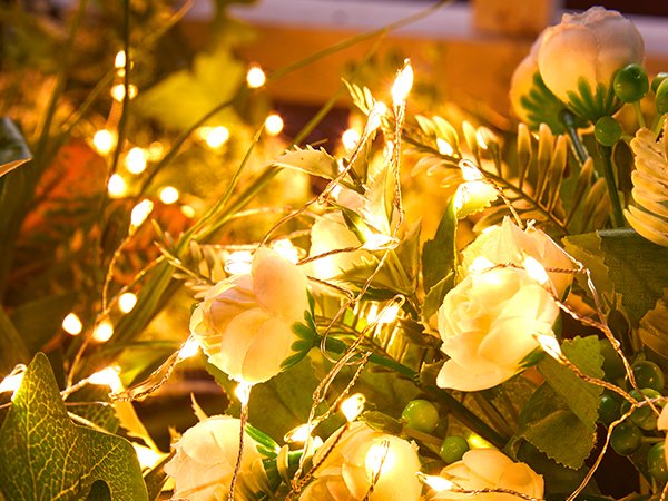 Firecracker fairy lights with silver wire wrapped around artificial flowers and greenery