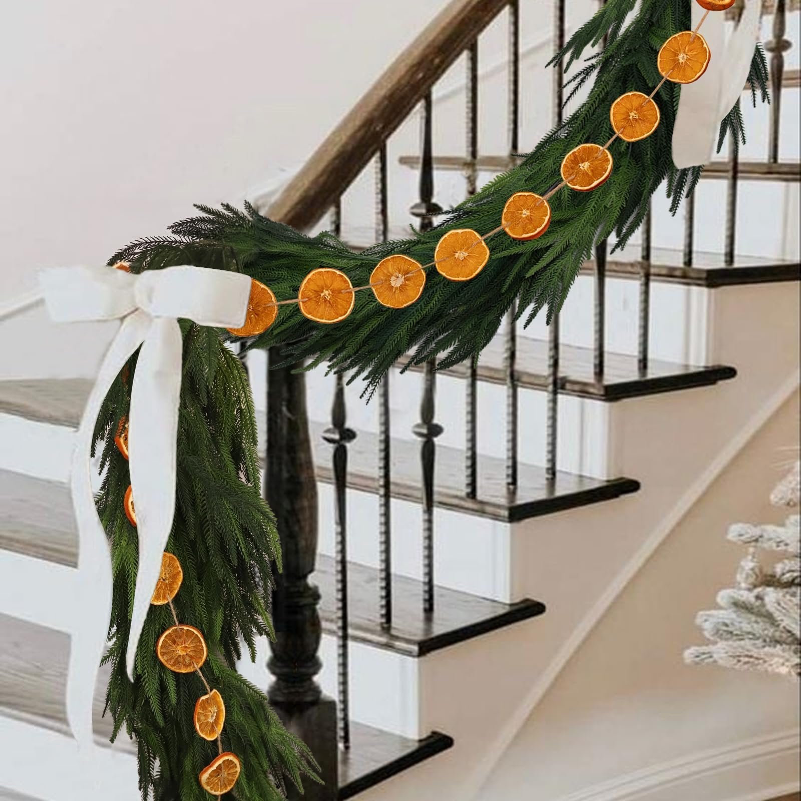 Dried orange slice garland draped on a staircase with green garland and white bows