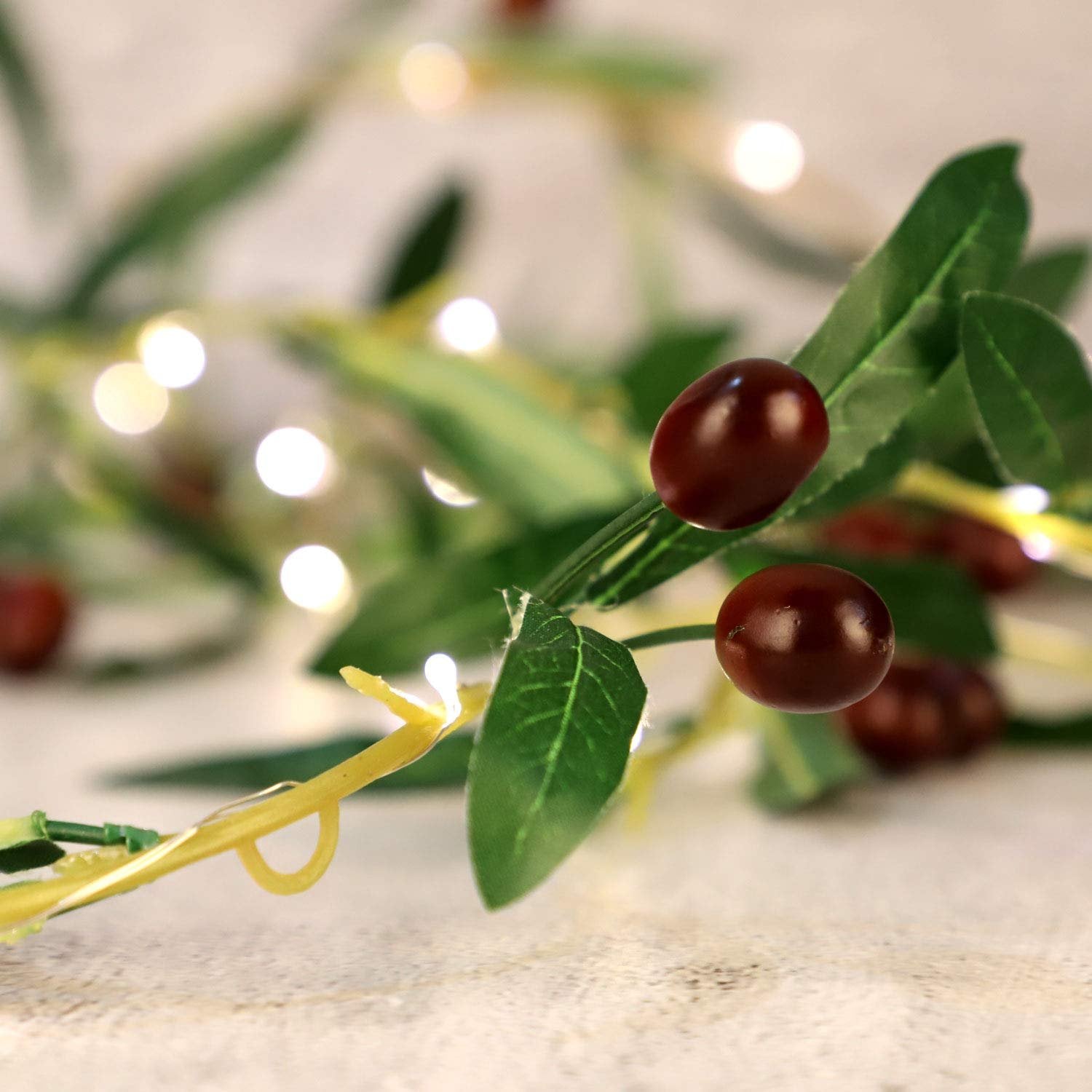 Close-up of an olive branch garland with warm white LED lights and faux olives.
