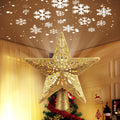 Golden glitter star Christmas tree topper with built-in LED snowflake projector casting snowflakes on the ceiling.