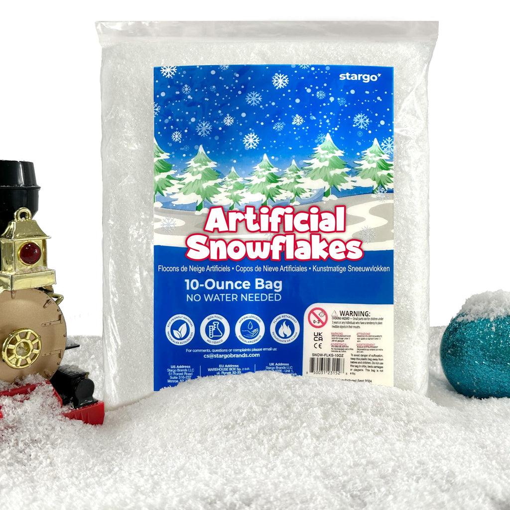 Bag of artificial snowflakes with a Christmas village scene on the packaging, surrounded by faux snow and a toy train.