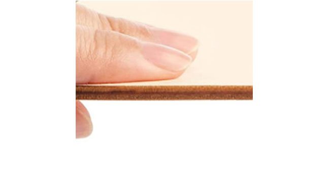 Close-up of a finger pressing down on the edge of a thin unfinished wood circle, showing its 1/8 inch thickness.