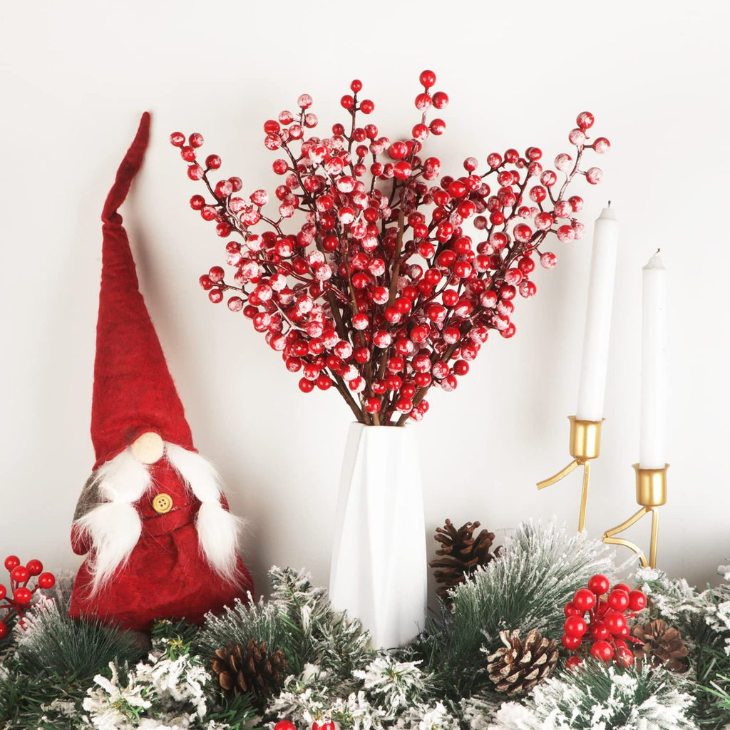 Christmas berry stems in a vase with a gnome and candles on a snowy garland
