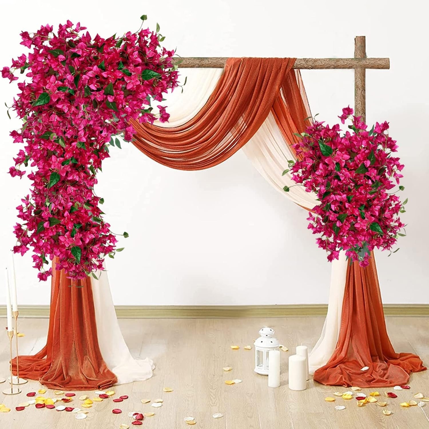 Artificial bougainvillea flower vines draped over a wooden arch with sheer fabric and scattered petals