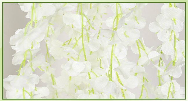 Close-up of cascading white artificial wisteria garland with green stems against a light background.