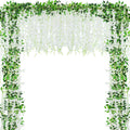 White artificial wisteria garland with green leaves draped in an arch shape against a white background.