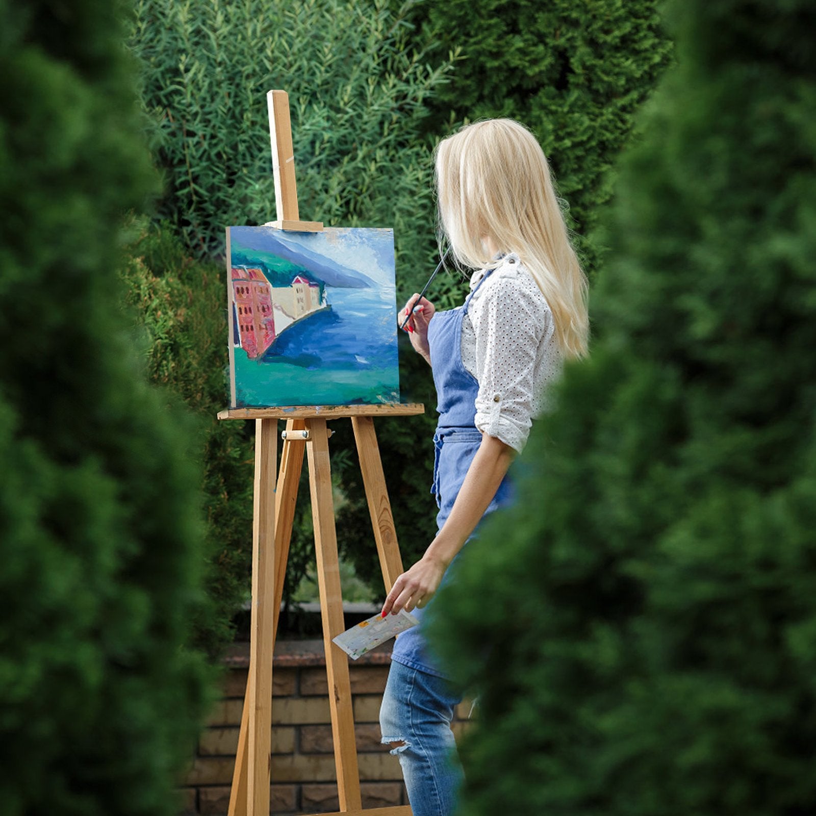 Woman painting a landscape on an easel outdoors, surrounded by greenery