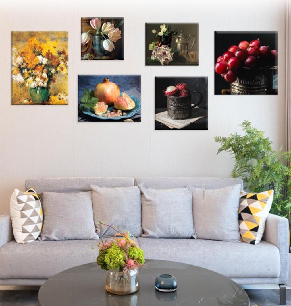 Six framed art prints of still life and floral arrangements hanging on a wall above a sofa.