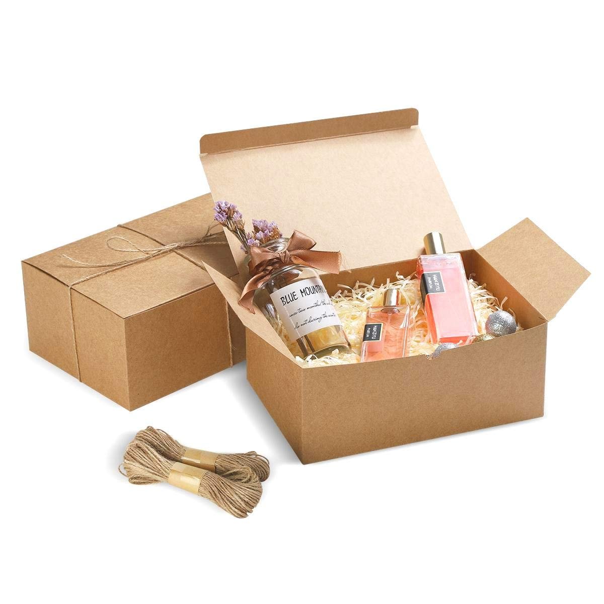 Brown cardboard gift boxes with lids, one open showing perfume bottles and decorative filler, with twine bundles nearby.