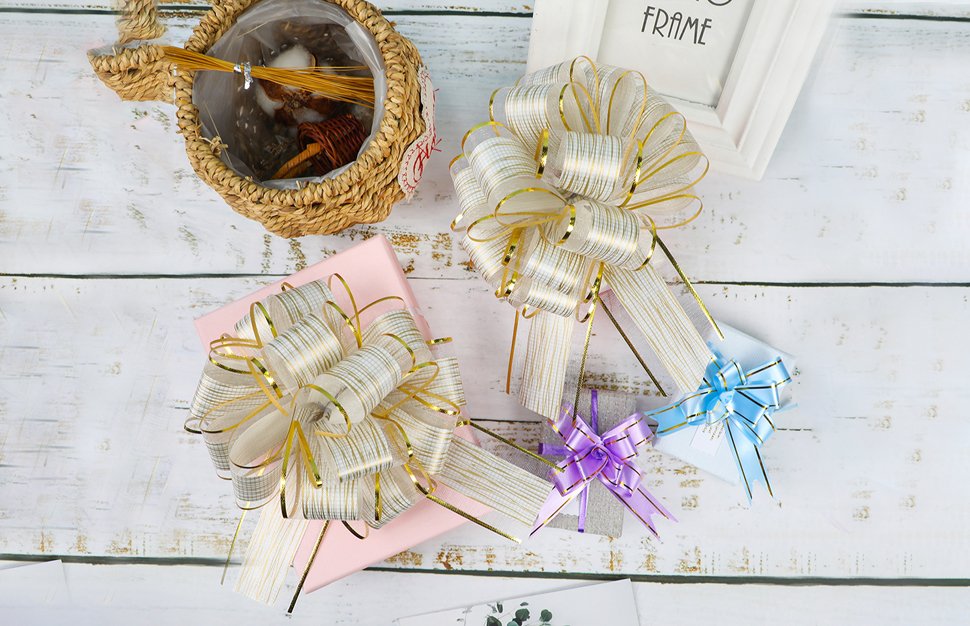 Three decorative pull bows on gift boxes, with a woven basket and a picture frame in the background.