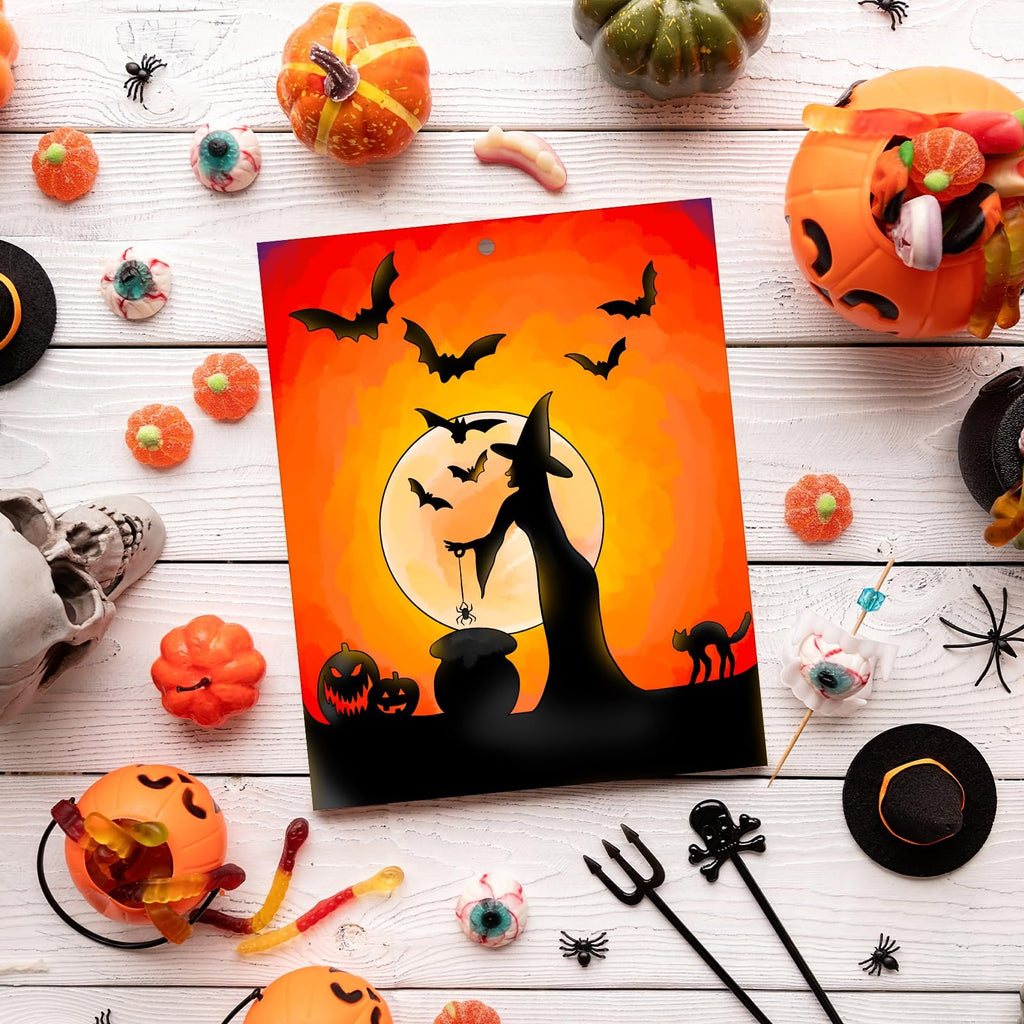 Halloween-themed unfinished wood ornament with witch, bats, and moon design, surrounded by candy and decorations on a white wooden table.