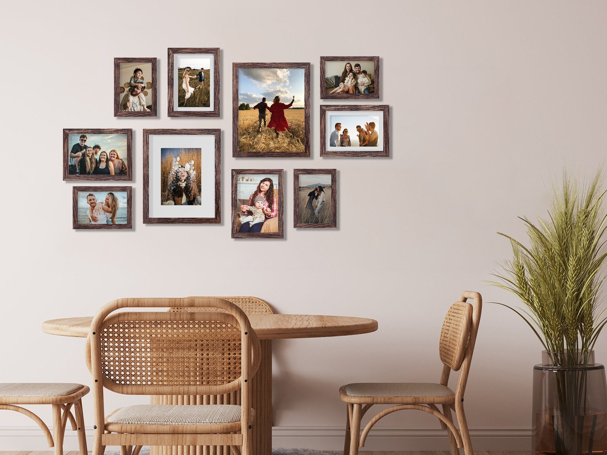 Gallery wall of ten dark wood picture frames displaying family photos on a light pink wall above a round wooden table and chairs.