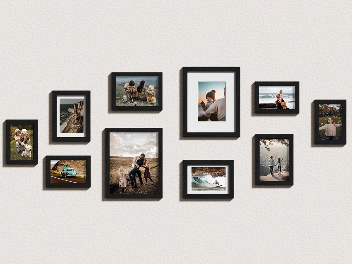 Gallery wall arrangement of ten black picture frames displaying various family and scenic photos on a textured white wall.