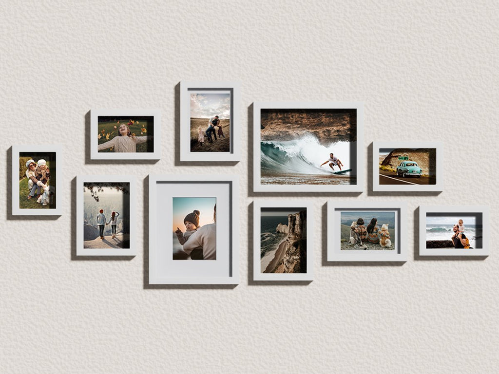 Gallery wall arrangement of ten white picture frames displaying various lifestyle photos on a textured wall.