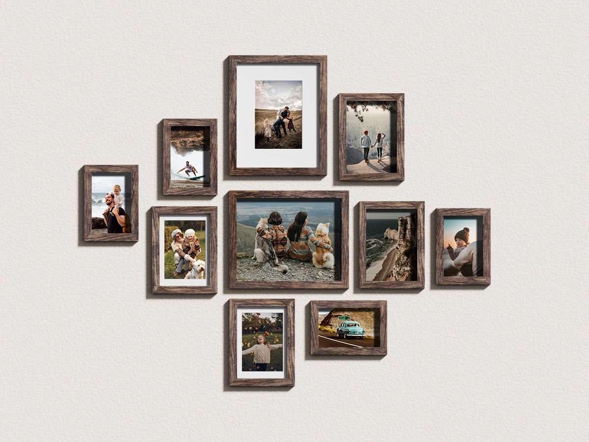 Gallery wall arrangement of ten dark wood picture frames displaying various family and scenic photos on a textured white wall.