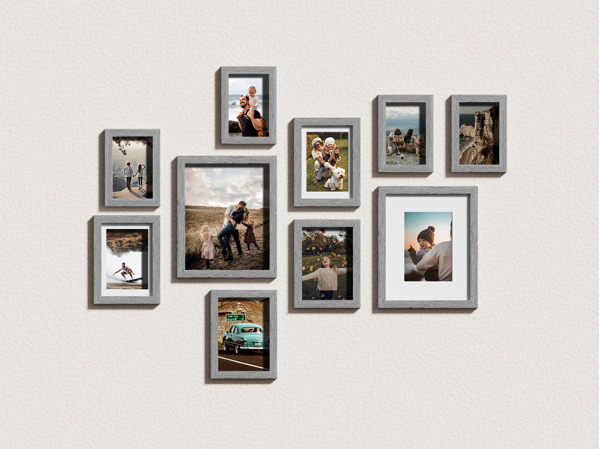 Gallery wall arrangement of ten grey picture frames displaying various family photos and scenic shots on a textured white wall.