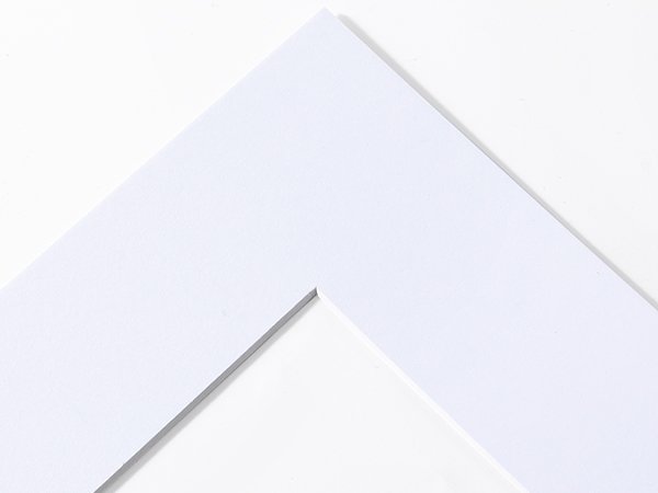 Close-up of a white picture frame mat with a clean white background, showing the corner edge.