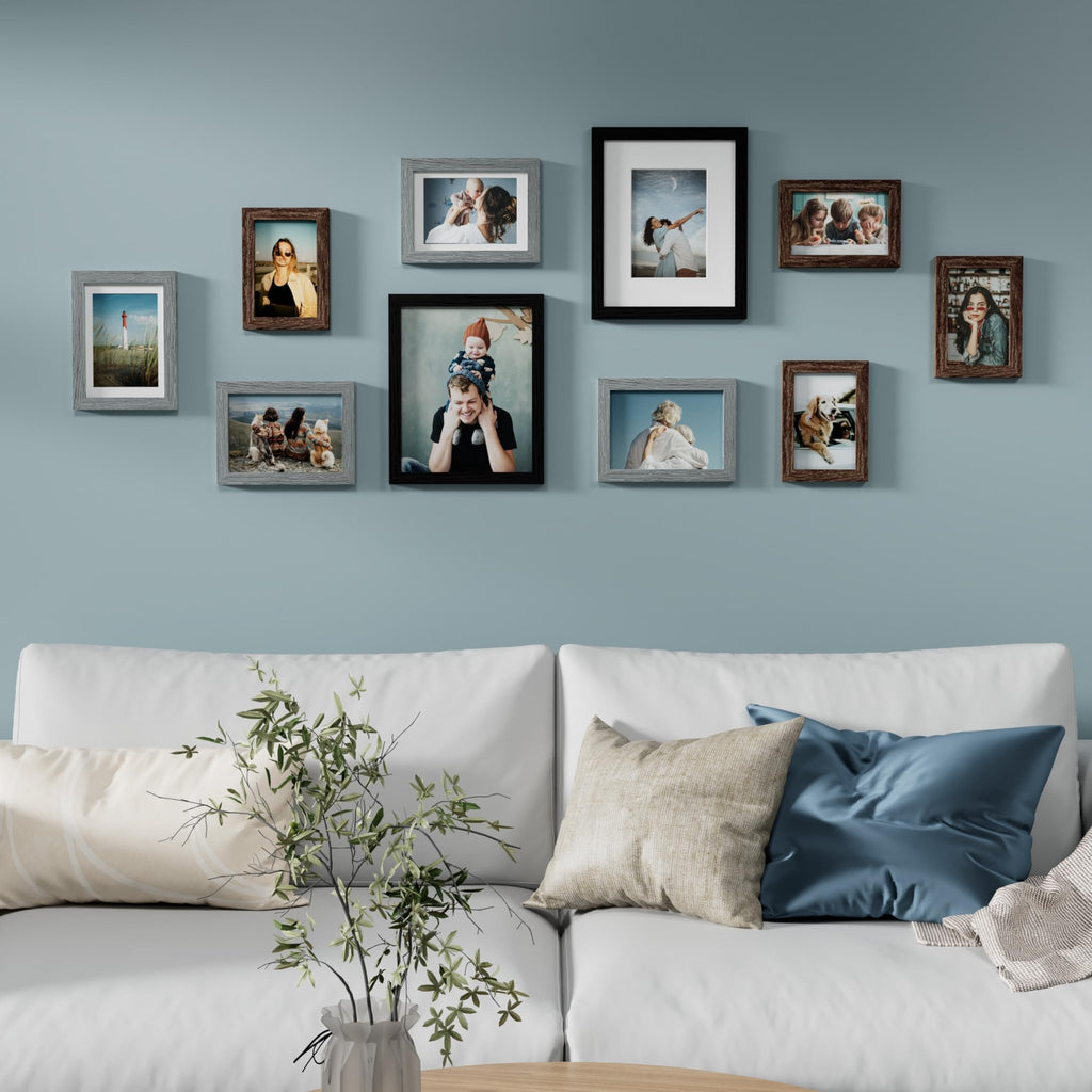 Gallery wall of ten picture frames in various sizes and colors arranged above a white sofa.