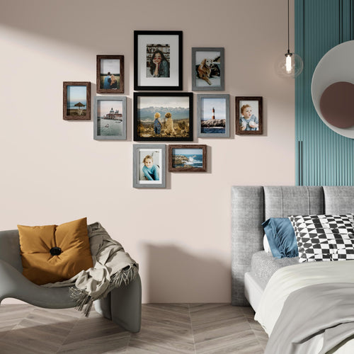 Gallery wall of ten picture frames arranged on a wall above a chair and bed. Frames display various photos.