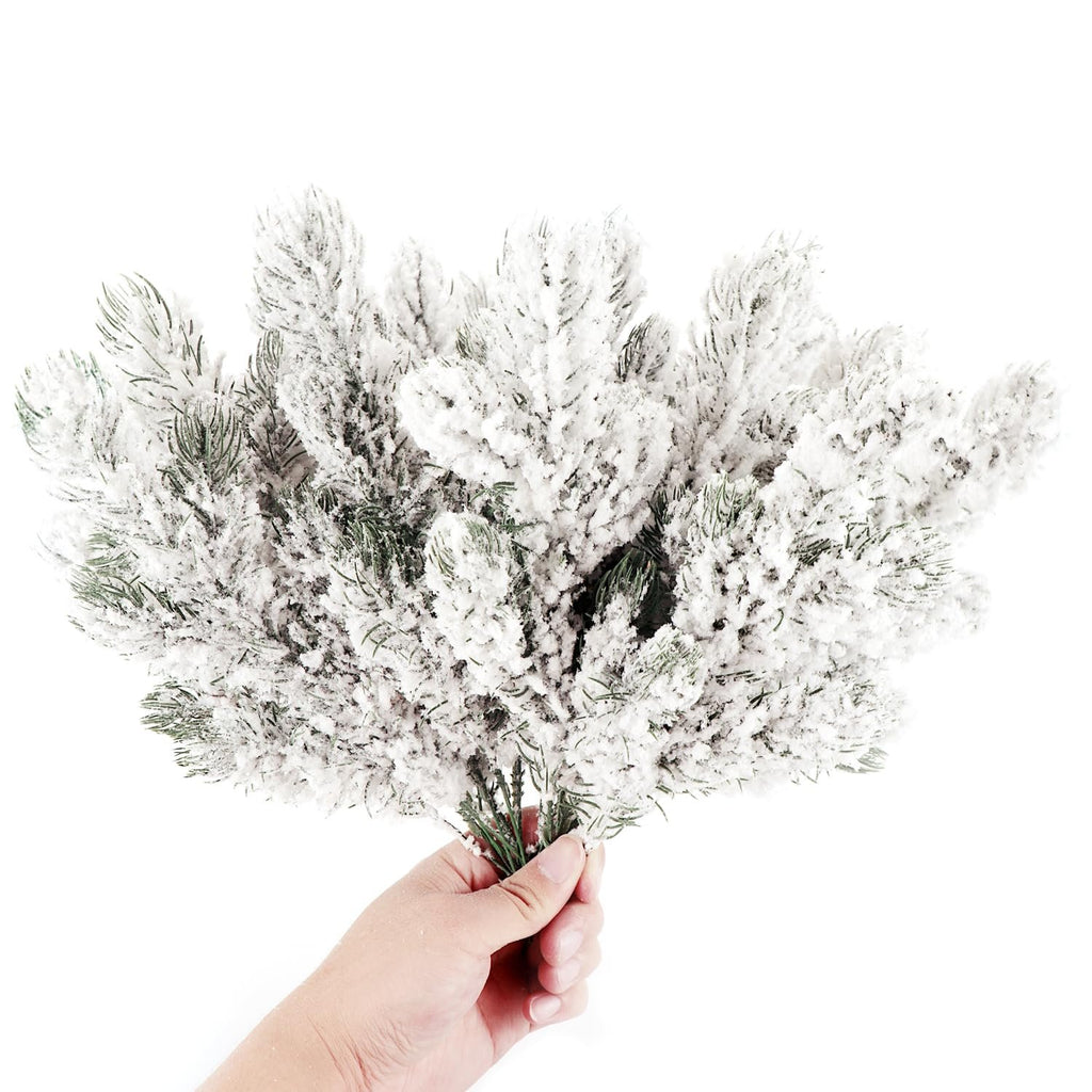 Hand holding frosted artificial pine needle branches with white snow effect