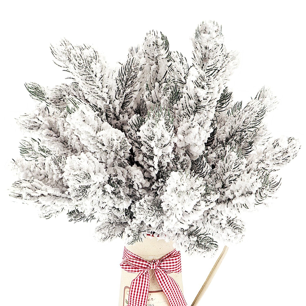 Frosted artificial pine needle branches with white snow in a decorative vase with a red and white checkered ribbon.