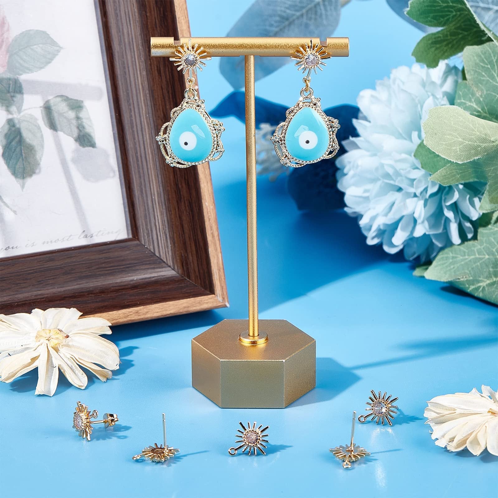 Gold plated sun earring findings with cubic zirconia and blue evil eye drop earrings on display stand